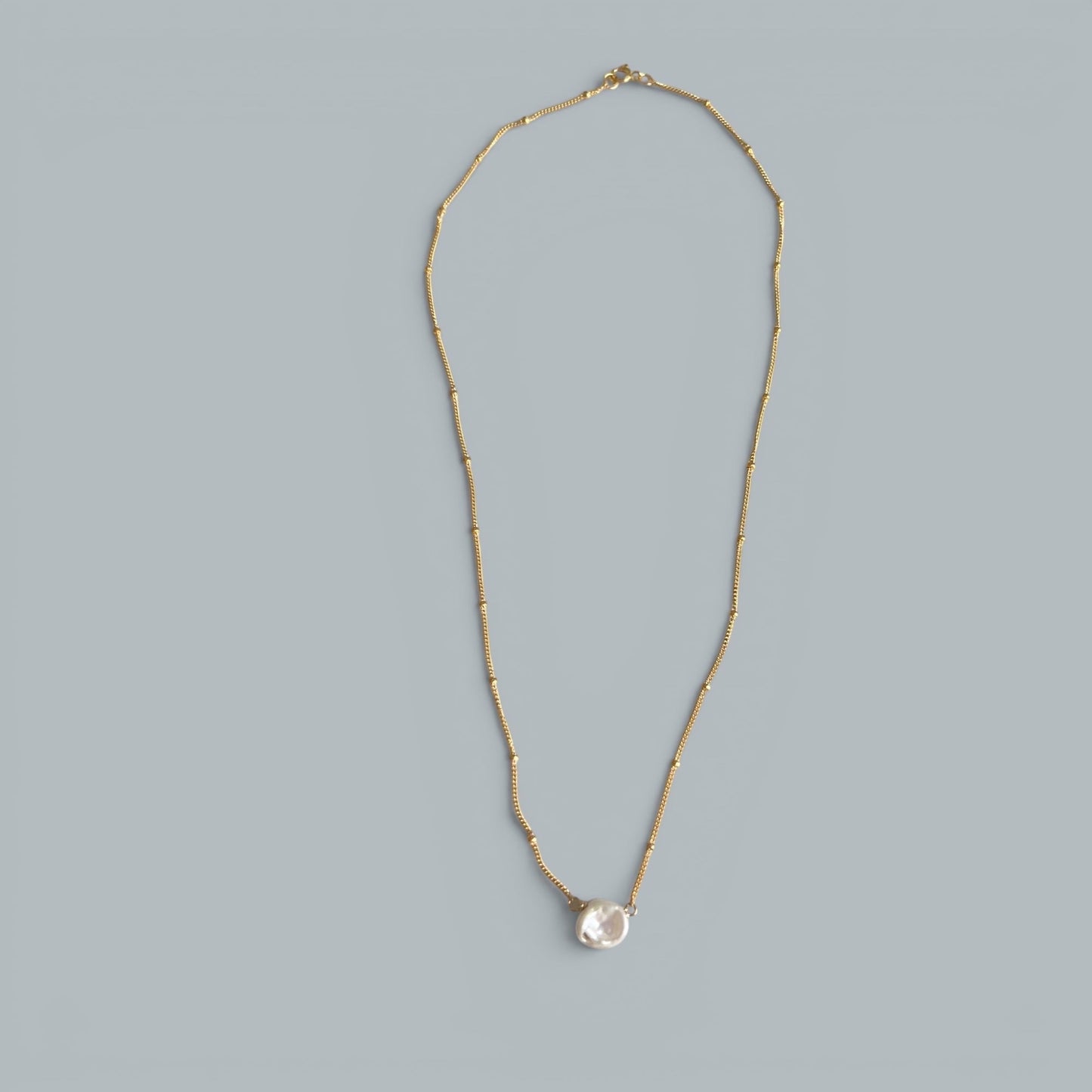 TSJ gold-tone chain necklace with a single baroque pearl pendant. Delicate and minimalist.