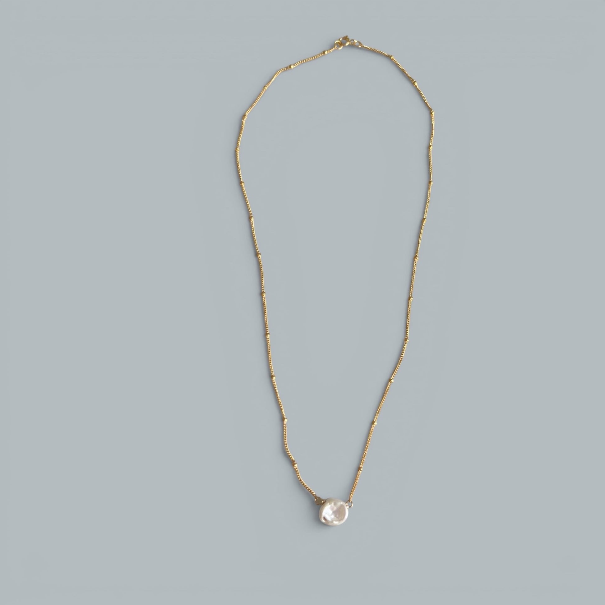 TSJ gold-tone chain necklace with a single baroque pearl pendant. Delicate and minimalist.
