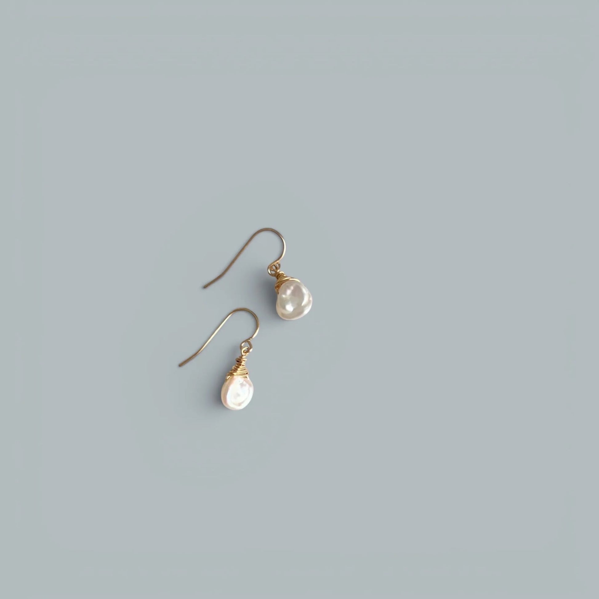 TSJ freshwater pearl drop earrings with gold-tone wire wrapping on a grey background.
